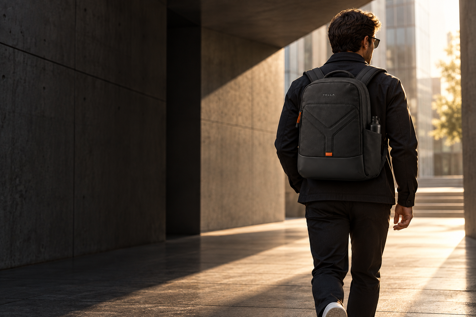 A traveler carrying a black YALLA backpack through modern city architecture